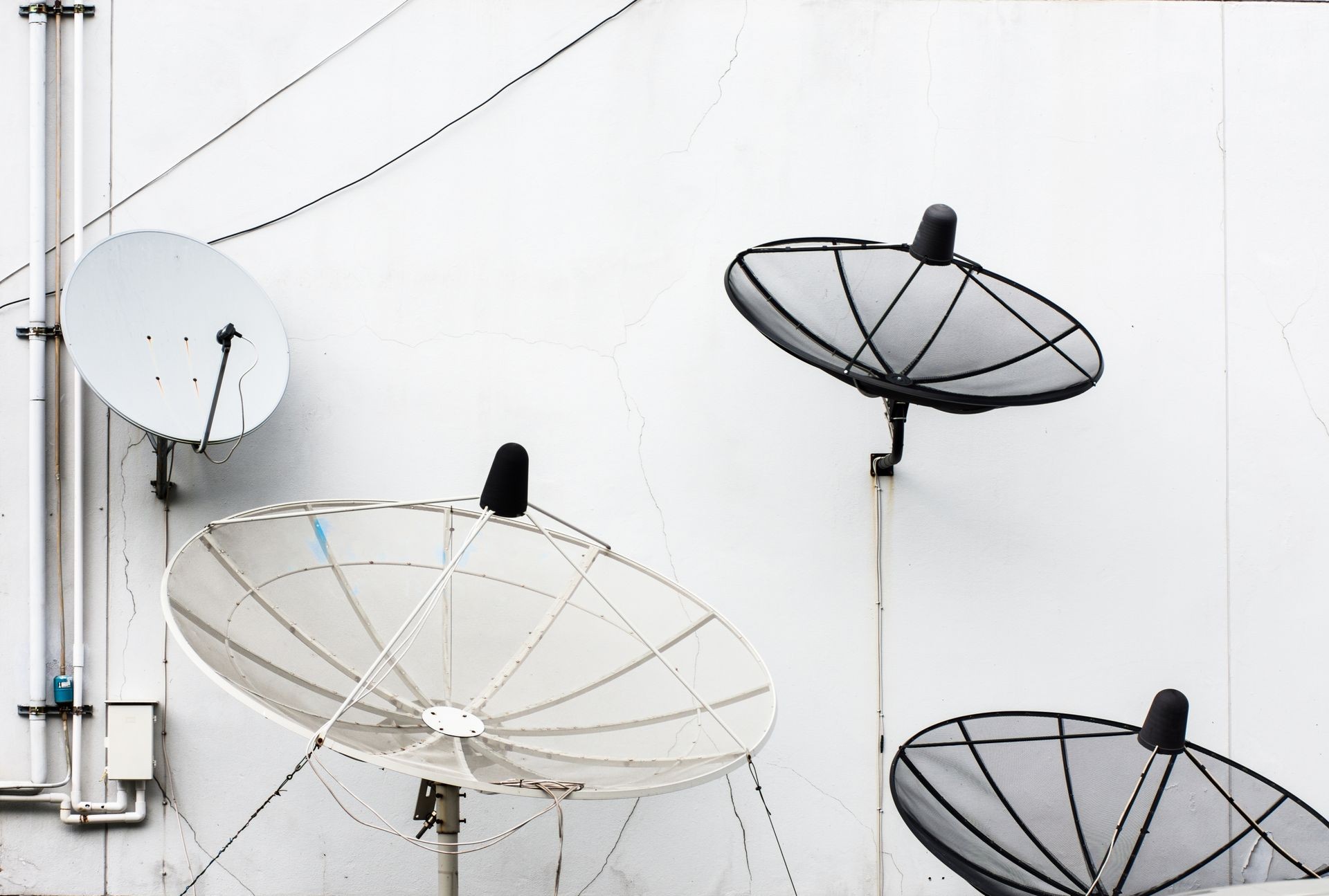 Many of satellites dishes install on the white wall.